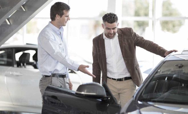 Cape Town, South Africa,car salesman pointing out new cars to male customer in showroom